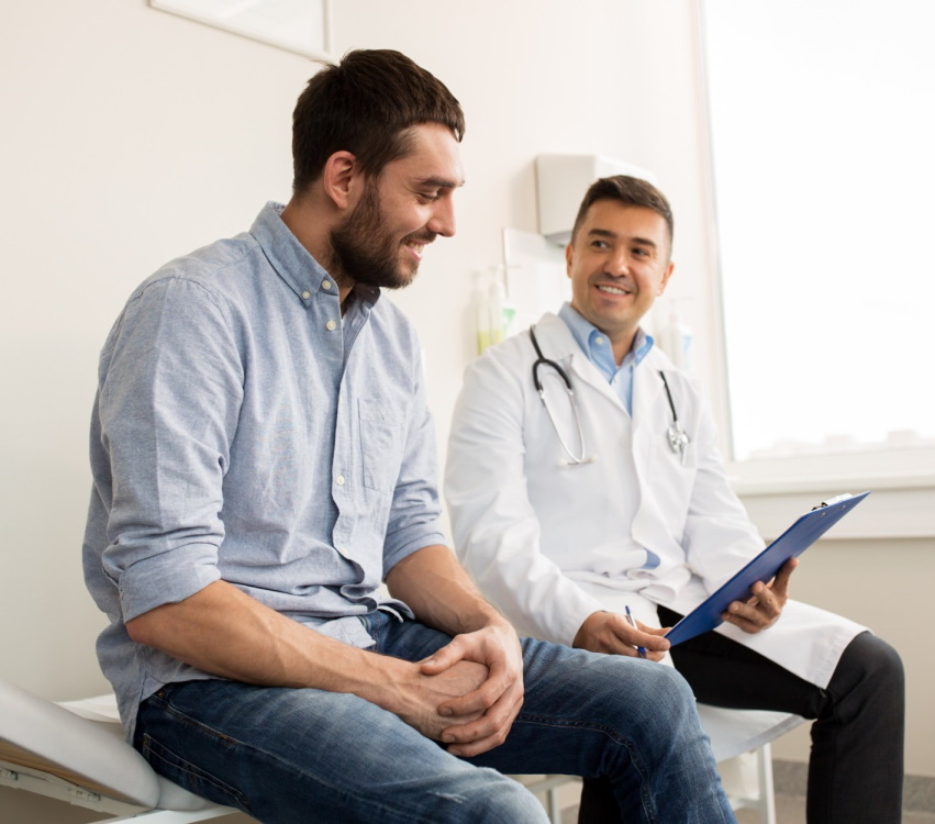 Friendly doctor talking with a smiling male patient during a consultation at MD Urgent Care clinic.